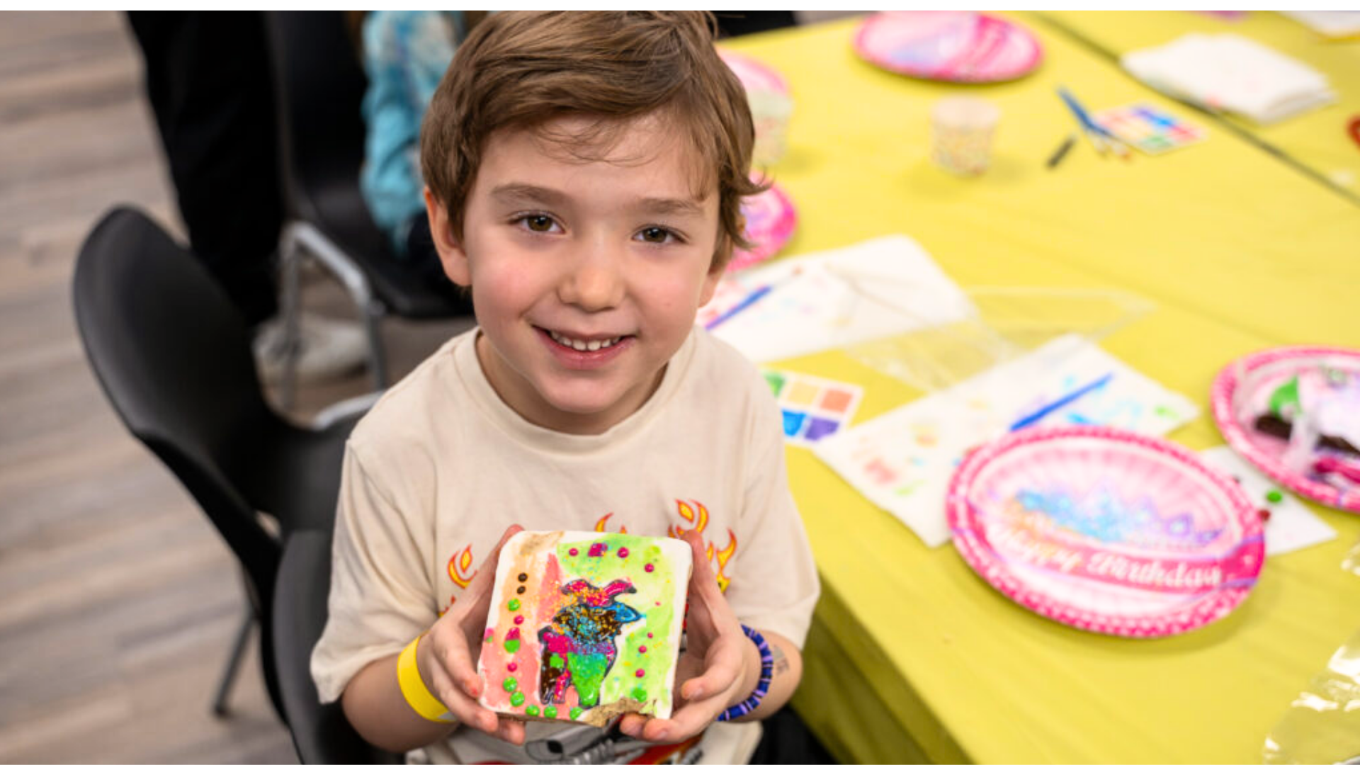 Smiling child proudly holding colorful artwork